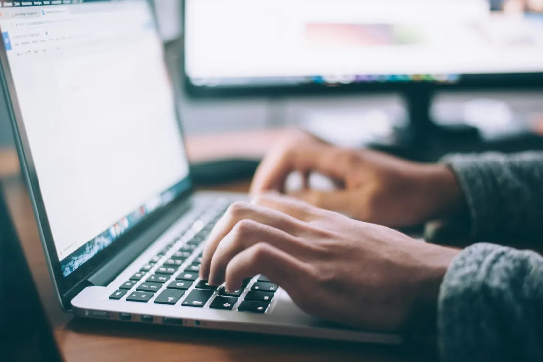 Person som skriver på en laptop med kontorsdokument på skärmen